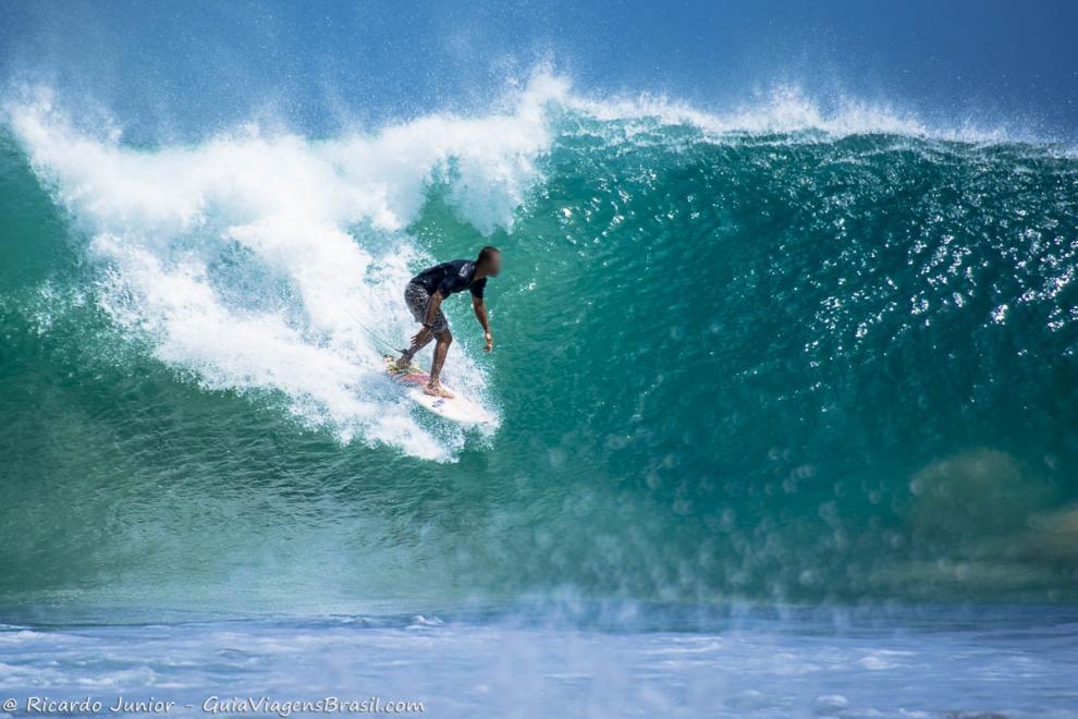 Imagem de surfista em pé na onda transparente de Noronha.